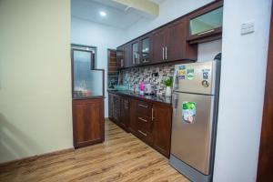 a kitchen with wooden cabinets and a stainless steel refrigerator at Villa Ceilaoo in Galle