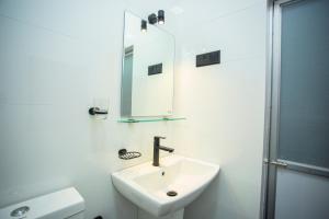 a white bathroom with a sink and a mirror at Villa Ceilaoo in Galle