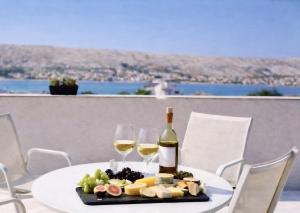 a table with two glasses of wine and a plate of food at Villa Una Maris - renovated 2026 in Pag