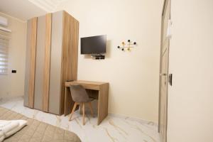 ein Schlafzimmer mit Schreibtisch und Fernseher an der Wand in der Unterkunft GioielliPlace in Capodrise