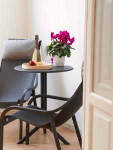 a table and a chair next to a table with a vase of flowers at ARIA Collection Bari in Bari