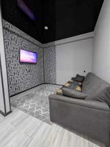 a room with a couch and a television on a wall at Gari's apartment next to Borjomi Central Park in Borjomi