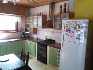 a kitchen with green cabinets and a white refrigerator at Chalet con pileta in Miramar