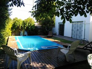 a swimming pool with two chairs and a table at Chalet con pileta in Miramar