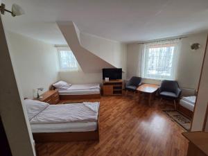 a room with two beds a desk and a tv at Apartamenty Cafe Wielbark in Wielbark