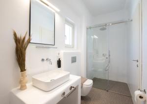 a white bathroom with a sink and a shower at Ventus Studios in Ano Mera
