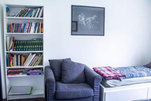 a room with a chair and a book shelf with books at Apartman Gajnice Zagreb in Zagreb