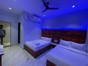 a room with two beds and a blue lighting at Hotel Midnight Lodging & Boarding in Panvel