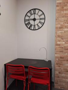 a table with two red chairs and a clock on the wall at LOFT La Placeta in Enguera