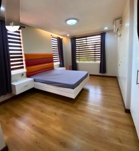 a bedroom with a bed and wooden floors and windows at Rathore villa in Lahore