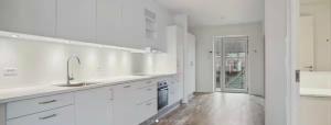 a white kitchen with white cabinets and a sink at Beach View Apartment in Vallensbæk in Vallensbæk