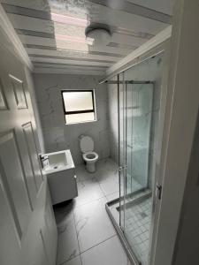 a bathroom with a glass shower and a toilet at Sunset Rest Guesthouse in Secunda