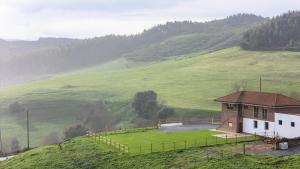 a house on a green hill with a tennis court at Finca Seles in Ajo