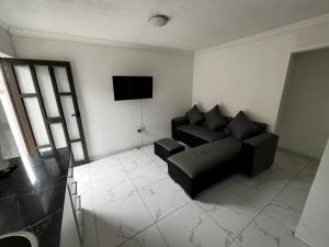 a living room with a black couch and a television at Sunset Rest Guesthouse in Secunda