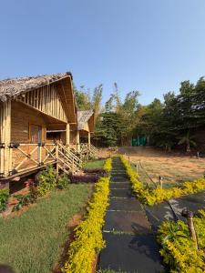 a path in front of a house with yellow flowers at Monkey Paradise Hampi in Hampi