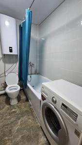a bathroom with a washing machine and a toilet at 1 комнатные апартаменты 4а 67 in Semey +2 photos