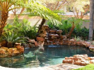 a swimming pool with a waterfall in a garden at Premier Hotel Pretoria in Pretoria