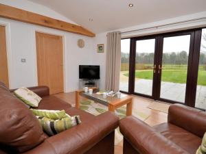 a living room with a leather couch and a television at 2 Bed in Chew Magna oc-chela in Stowey