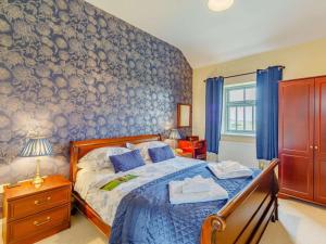 a bedroom with a bed with a blue patterned wall at 3 Bed in Consett oc-29408 in Lanchester