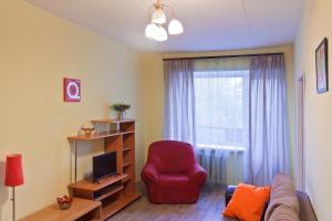 a living room with a red chair and a window at ALLiS-HALL Apartament at Karla Libkknekhta 16 in Yekaterinburg