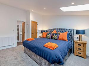 a bedroom with a large blue bed with orange pillows at 3 Bed in York oc-93897 in Tollerton