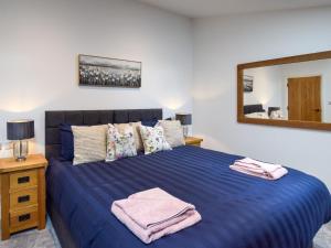 a bedroom with a blue bed with a mirror at 3 Bed in York oc-93896 in Tollerton