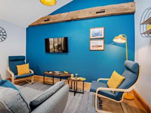 a living room with a blue wall and two chairs and a couch at 2 Bed in Axbridge oc-91358 in Loxton