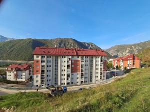 a building with a red roof on top of a hill at Apartman PETRA LUX in Plužine