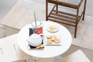 a table with a teapot and cookies and a drink at Approdo Rooms - Eja Sardinia in Cagliari