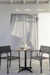 a table with two chairs and a white curtain at Livin Mykonos Hotel - Adults Only by Mr and Mrs White in Mikonos