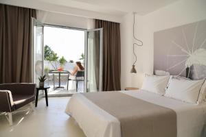 a white bedroom with a bed and a balcony at Livin Mykonos Hotel - Adults Only by Mr and Mrs White in Mikonos