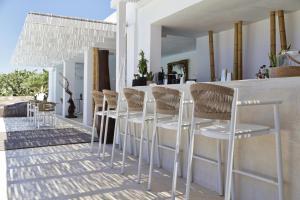 a group of white chairs sitting next to a counter at Livin Mykonos Hotel - Adults Only by Mr and Mrs White in Mikonos