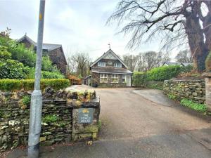 a house with a stone wall and a sign in front of it at The Mews Room at The Coach House in Windermere