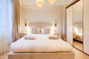 a bedroom with a large white bed and a mirror at London Central Residence in London