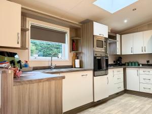 a kitchen with white cabinets and a window at JJs Lodge Jorvik in Walkington