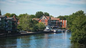 a river with houses and buildings next to a river at Uno Thames Hotel -Reopened Brand New Again -FREE PARKING in Maidenhead