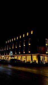 a lit up building with cars parked outside at night at Triple A Hotel in Riyadh