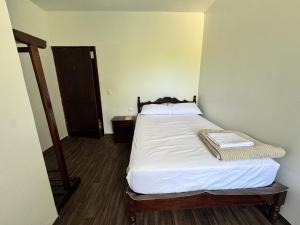 a small bedroom with a bed with white sheets at Puyo River Room in Puyo