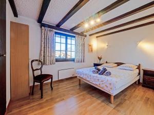 a bedroom with a bed and a chair and a window at Les Cassis in Nendaz
