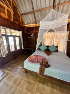 a bedroom with a bed with a mosquito net at Kwangpeeb Homestay in Ko Phayam