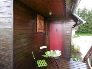a porch of a cabin with a table and a red door at chalet besse en chandese in Besse-et-Saint-Anastaise