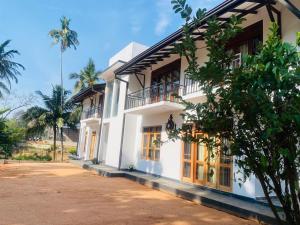 a white building with windows and a tree at Anchorage Apartment in Kurunegala