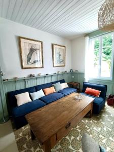 a living room with a blue couch and a wooden table at Le Cinquante-Trois, Maison Normande d'exception pour familles - Côte d'Albâtre in Saint-Valery-en-Caux