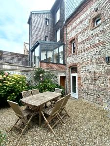 a wooden table and chairs in front of a brick building at Le Cinquante-Trois, Maison Normande d'exception pour familles - Côte d'Albâtre in Saint-Valery-en-Caux