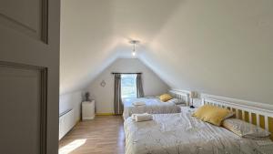 a attic bedroom with two beds and a window at Doonloughan View, Ballyconneely in Ballyconneely
