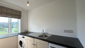 a kitchen with a sink and a washing machine at Doonloughan View, Ballyconneely in Ballyconneely +38 photos