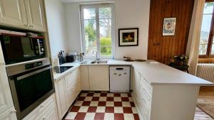 a kitchen with white cabinets and a checkered floor at Villa Tournevent - Villa d'exception avec vue Mer - Veules-les-Roses in Veules-les-Roses