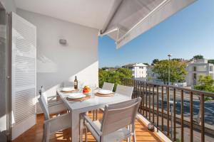 a dining room with a white table and chairs on a balcony at La Encina in Port d'Alcudia