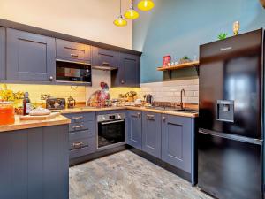 a kitchen with blue cabinets and a black refrigerator at 2 Bed in Ripon oc-94559 in Masham
