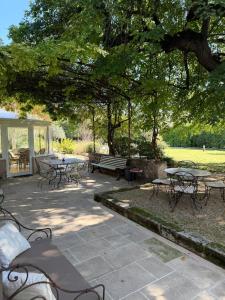 a patio with tables and chairs under a tree at Mas de la Meï in Cavaillon